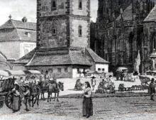Detail rytiny, zobrazujúcej centrum Košíc v stave okolo roku 1835. Okolo krámikov, pristavaných pod Urbanovou vežou, sa zhromažďovali trhovci. Zaujímavé sú sochy pred severným vstupom do dómu.