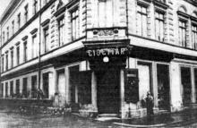 Nárožie dvojposchodovej budovy, ktorá starú zbrojnicu nahradila. Fotografia pochádza z roku 1909, keď už v budove sídlilo riaditeľstvo mestských lesov a v prízemí lekáreň "U vykupiteľa".